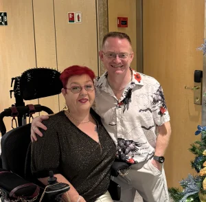 Jeff & Caroline sat next to a Christmas tree.